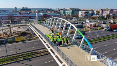 Grupa ludzi testuje nowo powstałą kładkę dla pieszych nad ulicą Struga w Szczecinie która została zrealizowana z SBO